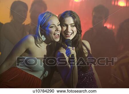 Stock Image - Women singing karaoke. Fotosearch