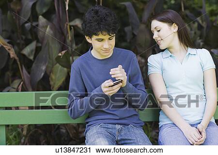 Young couple sitting on park bench View Large Photo Image Stock Image - Young couple sitting on park bench. Fotosearch