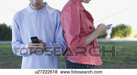 Stock Photo - Young couple text messaging outdoors. Fotosearch