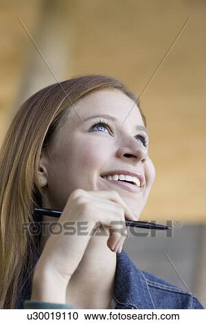 Stock Image - Young woman holding pen. Fotosearch