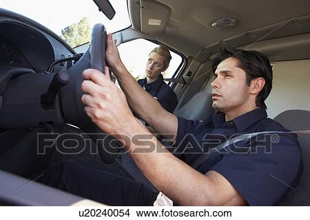 Picture - Ambulance driver and colleague on the way to an emergency. Fotosearch