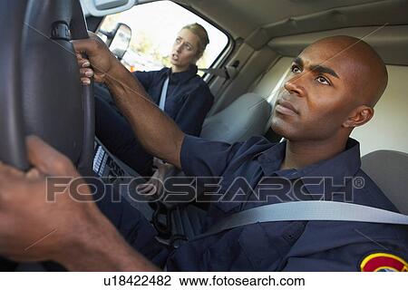 Stock Image - Ambulance driver and colleague on the way to an emergency. Fotosearch