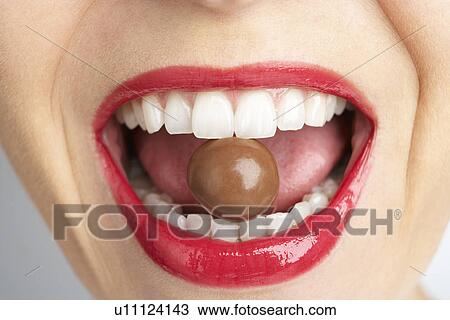 Stock Image - Close-Up Of Woman's Mouth Biting On Chocolate. Fotosearch