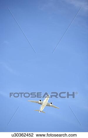 Commercial Airplane Flying Against A Blue Sky View Large Photo Image Stock Image - Commercial Airplane Flying Against A Blue Sky. Fotosearch