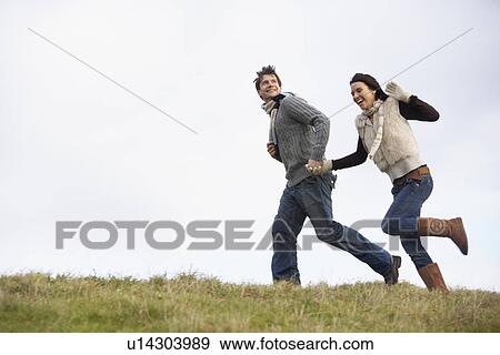 Stock Photo - Couple Holding Hands And Running In The Park. Fotosearch