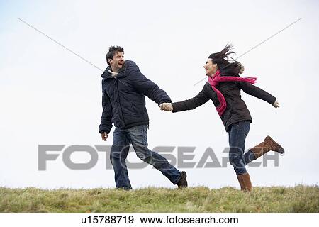 Stock Photo - Couple Holding Hands And Running In The Park. Fotosearch