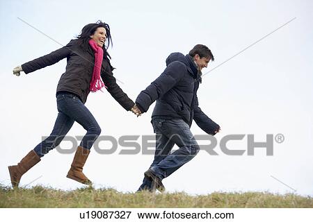 Stock Photo - Couple Holding Hands And Running In The Park. Fotosearch