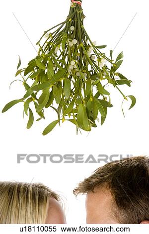 Stock Photography - Couple Standing Beneath Mistletoe Against White Background. Fotosearch