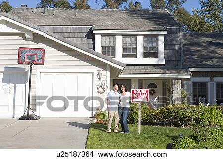 Couple Standing Outside House With Real Estate Sign View Large Photo Image Picture - Couple Standing Outside House With Real Estate Sign. Fotosearch