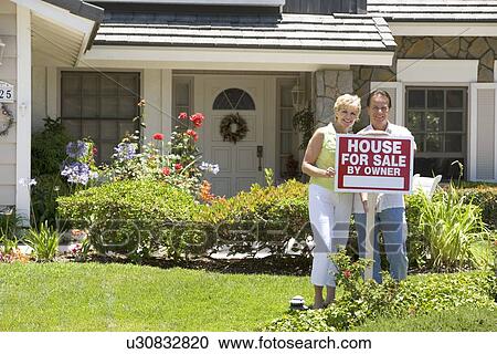 Couple Standing Outside House With Real Estate Sign View Large Photo Image Stock Image - Couple Standing Outside House With Real Estate Sign. Fotosearch