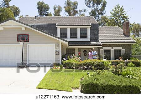 Stock Image - Couple Standing Outside Their House. Fotosearch