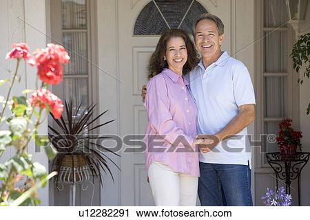 Stock Image - Couple Standing Outside Their House. Fotosearch