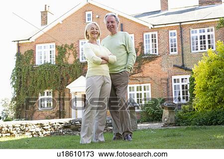 Stock Image - Couple Standing Outside Their House. Fotosearch