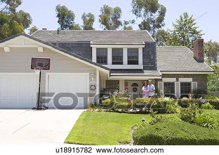 Stock Image - Couple Standing Outside Their House. Fotosearch