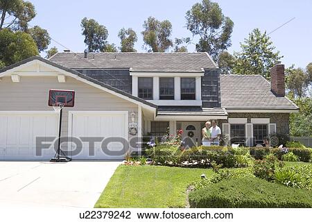 Stock Image - Couple Standing Outside Their House. Fotosearch