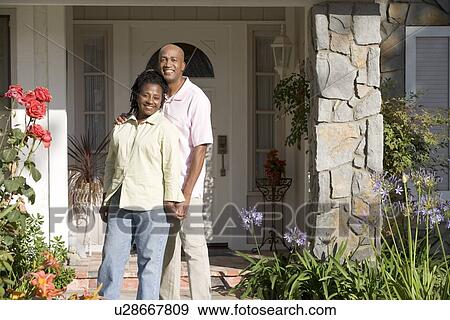 Stock Photo - Couple Standing Outside Their House. Fotosearch
