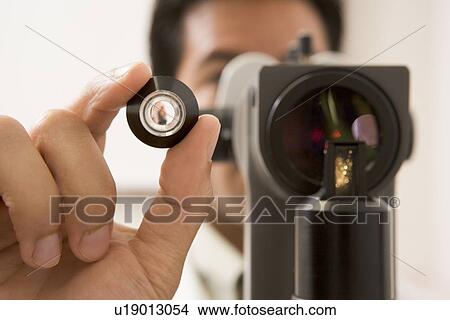 Picture - Doctor Looking Through Eye Exam Machine . Fotosearch