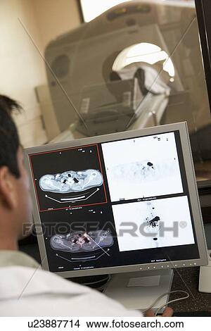Picture - Doctor Monitoring Patient Having Computerized Axial Tomography (CAT) Scan. Fotosearch