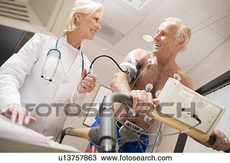 Stock Image - Doctor Monitoring The Heart-Rate Of Patient On A Treadmill. Fotosearch