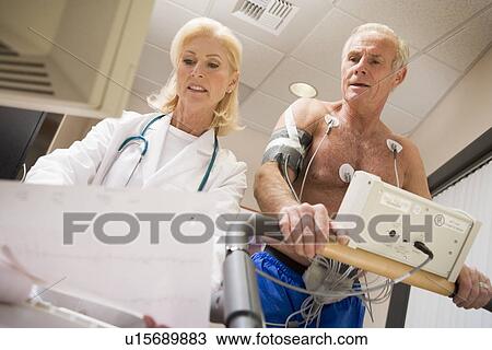 Stock Image - Doctor Monitoring The Heart-Rate Of Patient On A Treadmill. Fotosearch
