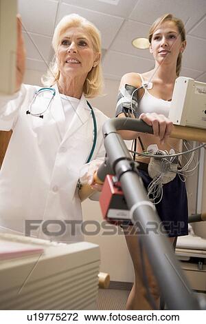 Stock Image - Doctor Monitoring The Heart-Rate Of Patient On A Treadmill. Fotosearch