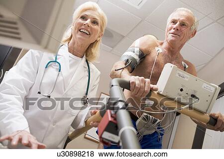 Stock Photo - Doctor Monitoring The Heart-Rate Of Patient On A Treadmill. Fotosearch