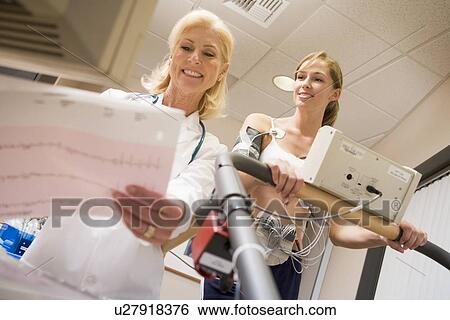 Stock Photograph - Doctor Monitoring The Heart-Rate Of Patient On A Treadmill. Fotosearch