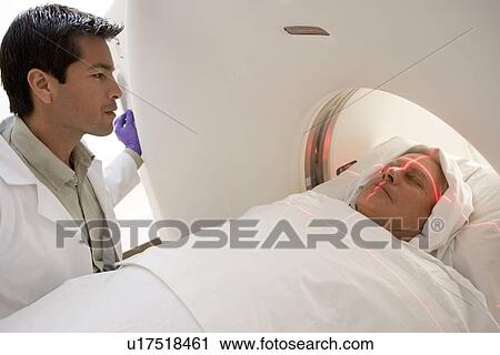 Stock Image - Doctor With Patient Having A Computerized Axial Tomography (CAT) Scan. Fotosearch