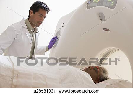 Stock Image - Doctor With Patient Having A Computerized Axial Tomography (CAT) Scan. Fotosearch