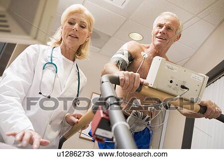 Stock Image - Doctor With Patient While They Run Being Monitored. Fotosearch