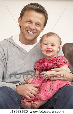 Stock Image - Father And Baby Daughter On Sofa. Fotosearch