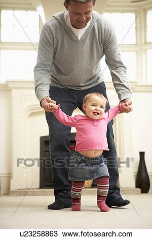 Stock Image - Father Helps Baby Daughter With Walking. Fotosearch