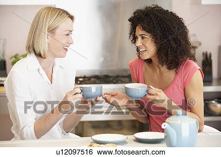 Stock Photograph - Female Friends Enjoying Tea And Cookies At Home. Fotosearch
