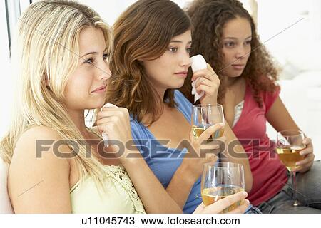 Stock Image - Female Friends Watching A Sad Movie Together. Fotosearch