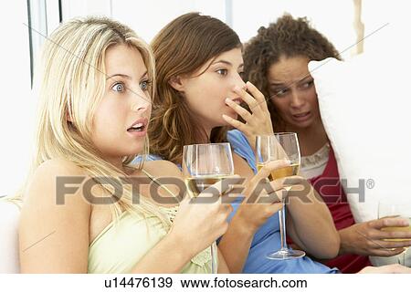 Stock Photo - Female Friends Watching A Scary Movie Together. Fotosearch