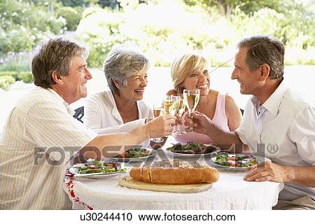 Stock Image - Friends Eating An Al Fresco Lunch, Holding Wineglasses. Fotosearch