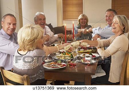 Stock Photo - Friends Pulling Christmas Crackers At A Dinner Party. Fotosearch