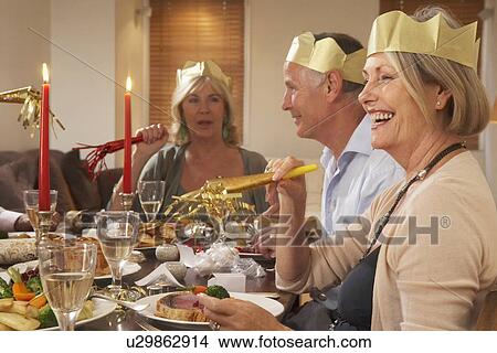 Picture - Friends Wearing Party Hats At A Dinner Party. Fotosearch