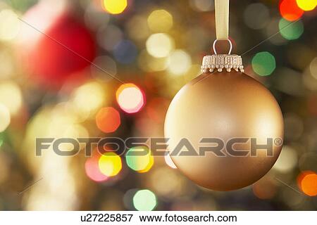Stock Photo - Gold Bauble Hanging On Decorated Tree. Fotosearch