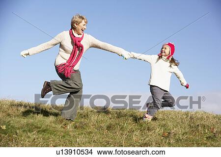 Picture - Granddaughter Running And Pulling Grandmother By The Hand. Fotosearch