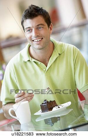 Stock Image - Man Eating A Piece Of Cake At The Mall. Fotosearch