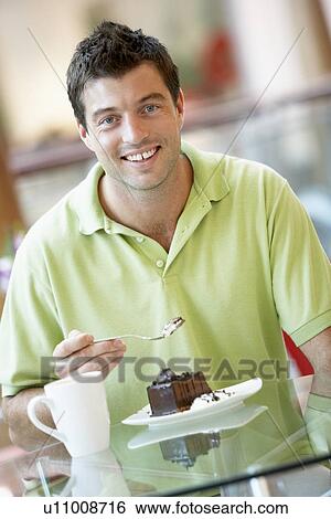 Stock Photograph - Man Eating A Piece Of Cake At The Mall. Fotosearch