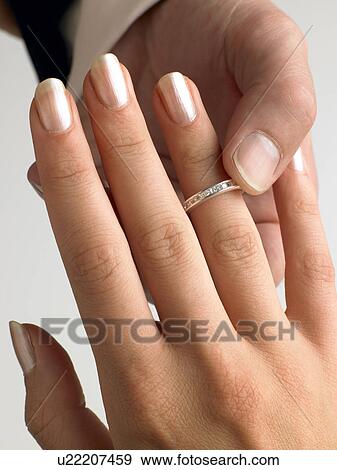 Stock Photo - Man Putting Diamond Ring On Woman's Finger. Fotosearch