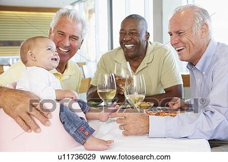 Stock Photo - Man Showing His Baby Granddaughter To Friends At A Restaurant. Fotosearch