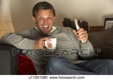 Man With Coffee Watching Television Excitedly View Large Photo Image Stock Image - Man With Coffee Watching Television Excitedly. Fotosearch