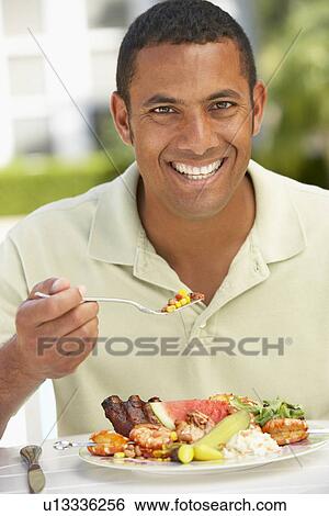 Stock Photograph - Mid Adult Man Dining Al Fresco. Fotosearch