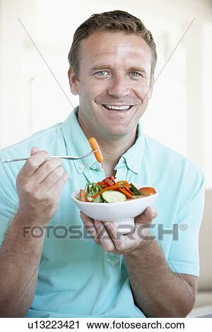 Stock Image - Mid Adult Man Eating A Salad. Fotosearch