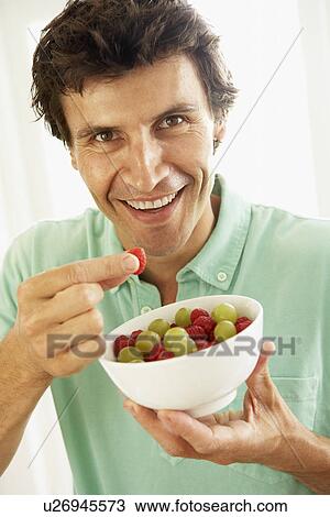 Stock Image - Mid Adult Man Eating Fresh Fruit. Fotosearch