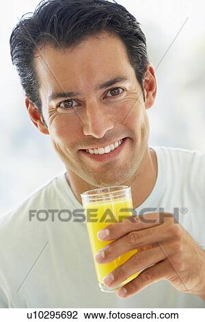 Stock Image - Mid Adult Man Smiling At The Camera And Drinking Orange Juice. Fotosearch