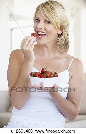 Stock Image - Mid Adult Woman Eating A Bowl Of Strawberries. Fotosearch